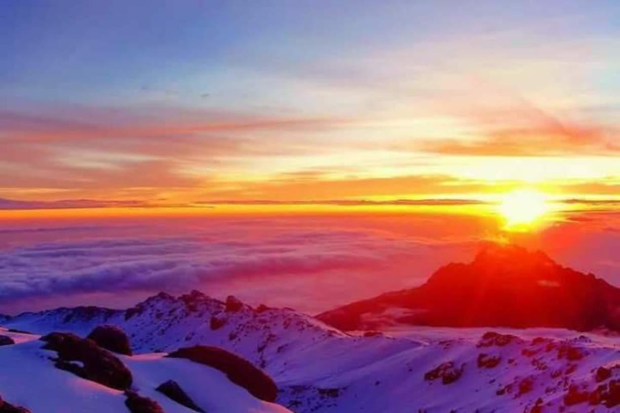 Sunrise above the clouds from high on Kilimanjaro, with snow in the foreground