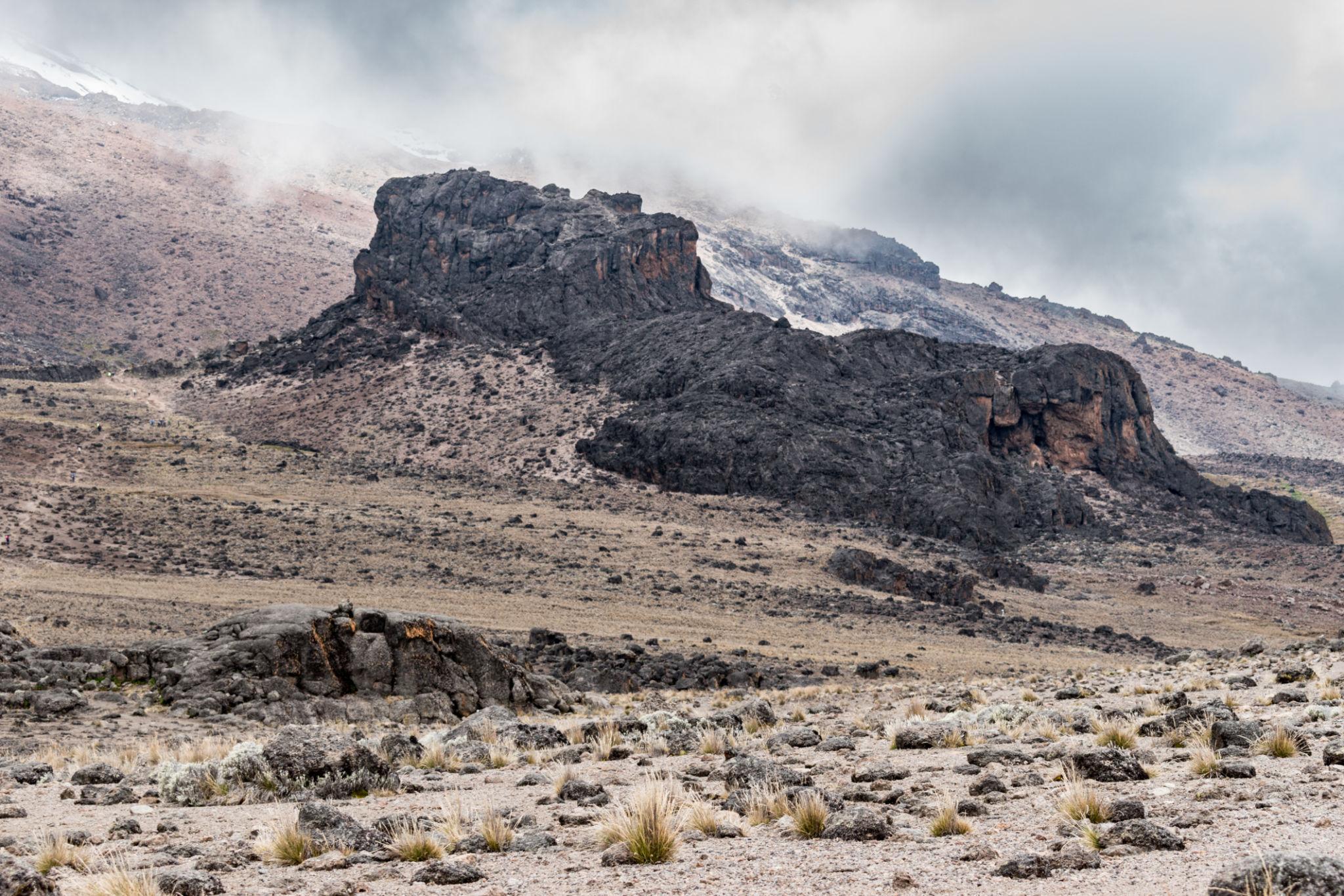 A dark volcanic rock outcrop in cloud on a high, snowy slope