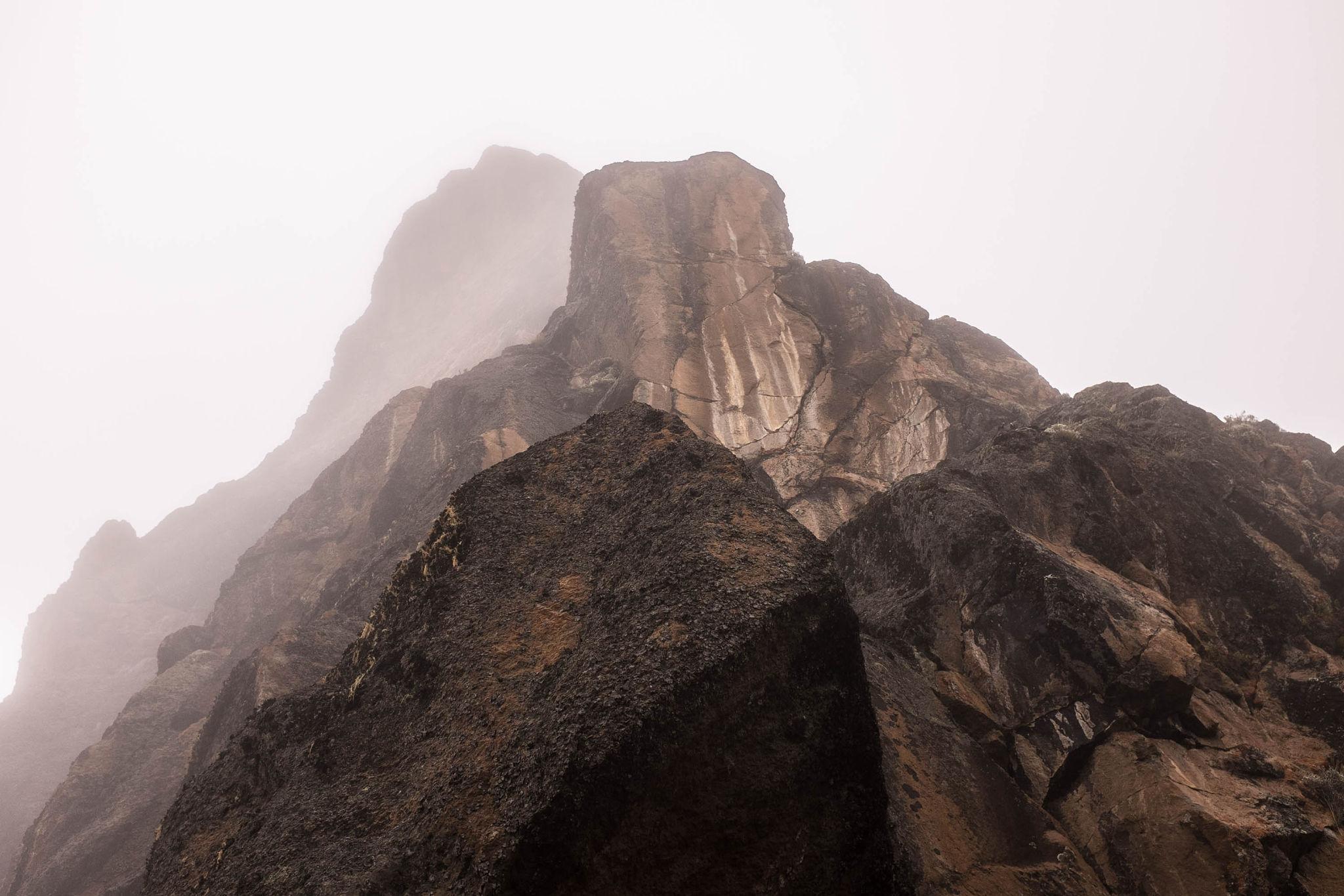 A tall dark rock tower half hidden in mist