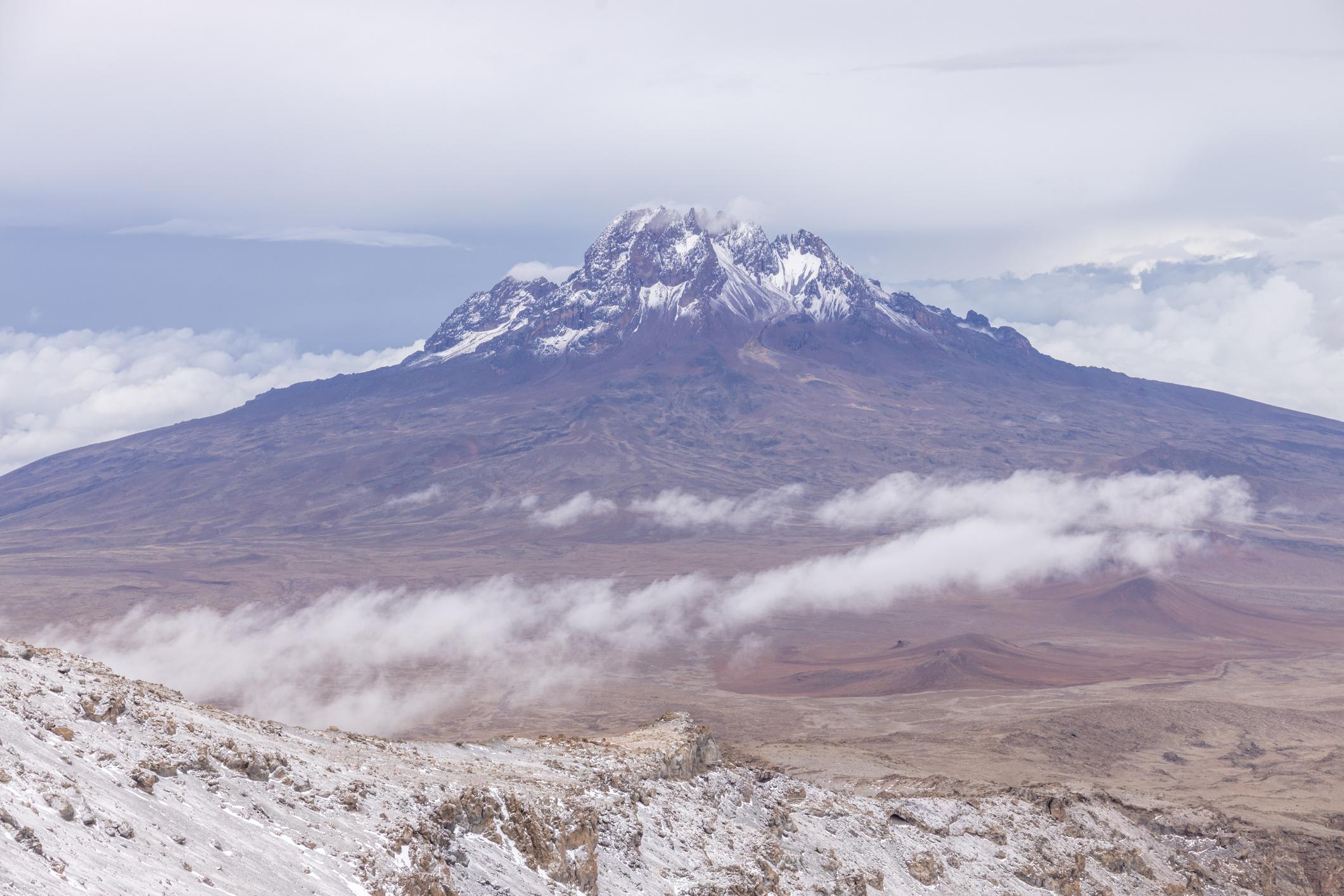 The jagged snow-dusted peak of Mawenzi rising above a layer of cloud